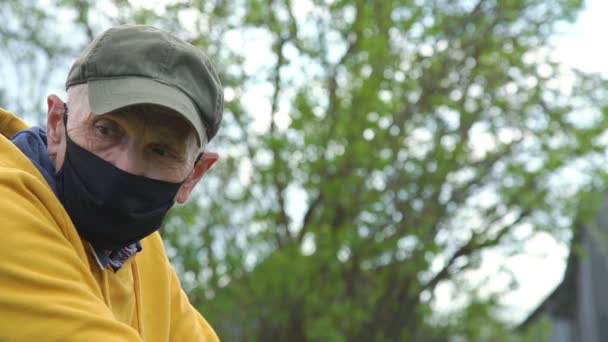Senior hombre en negro máscara espera productos por árboles primer plano — Vídeos de Stock