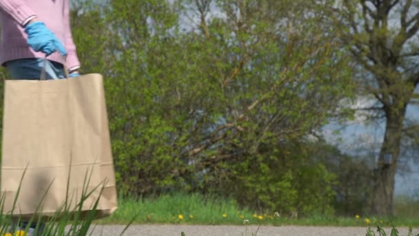 Dívka v džínách přináší papírové tašky klade na silnici starý muž bere — Stock video