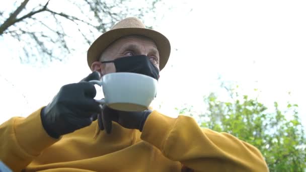 Pensionista en guantes de máscara da taza a chica contra el cielo gris — Vídeos de Stock