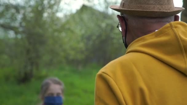 Kleindochter opa in maskers spelen met bal in de tuin — Stockvideo