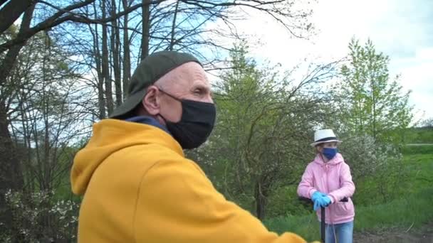 Morfar och barnbarn i masker pratar på byvägen — Stockvideo