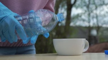 Eldivenli kız plastik şişeden su dolduruyor.