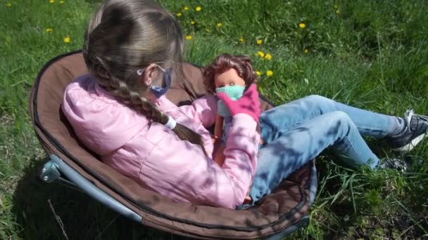 Scolaretta in guanti sterili e maschera gioca con bambola in sedia — Video Stock