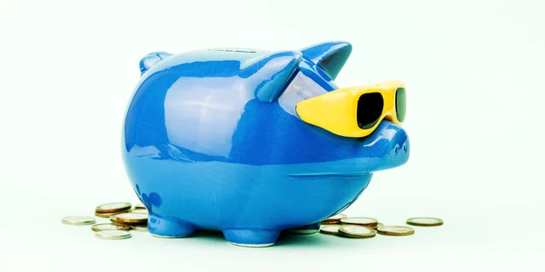 Blauwe spaarpot met gele zonnebril tussen de munten — Stockfoto