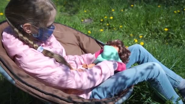 Girl in gloves plays with doll putting mask among garden — Stock Video