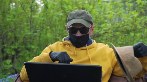 Pensioner na máscara tenta no chapéu conversando no laptop close-up — Vídeo de Stock