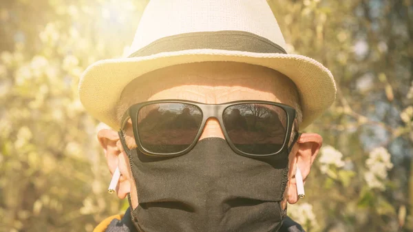 Пожилой мужчина в одноразовой маске слушает музыку в наушниках — стоковое фото
