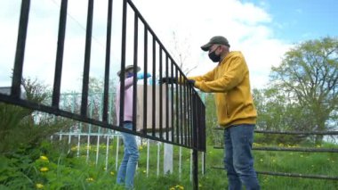 Liseli kız, maske takmış yaşlı bir adama yiyecek getiriyor.