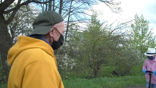 Oude man en jonge dame met maskers stoppen op afstand om te begroeten — Stockvideo
