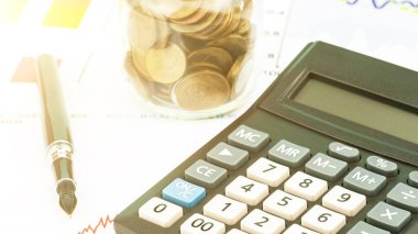 Siyah tüy kaleminin yanında renkli düğmeleri olan hesap makinesi var