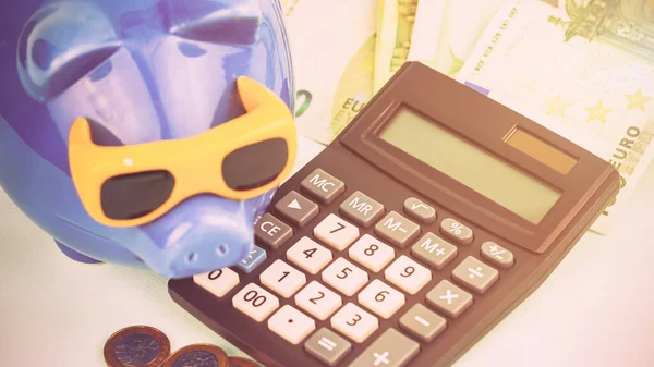 Engraçado azul porquinho banco de forma de porco perto de grande calculadora — Fotografia de Stock