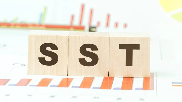 Masadaki tahta küplerin üzerinde farklı grafiklerle sst harfleri var.