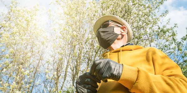 Alter Gärtner mit sterilen Maskenhandschuhen im gelben Kapuzenpullover — Stockfoto