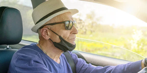 pensioner in white hat and black mask drives car closeup