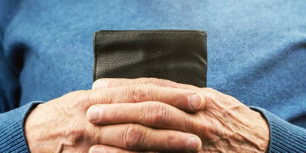 Pessoa idosa em mãos pulôver azuis segurar pequena carteira preta — Fotografia de Stock