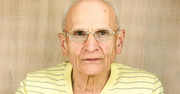 Пожилой человек в очках и пуловер смотрит в камеру близко — стоковое фото