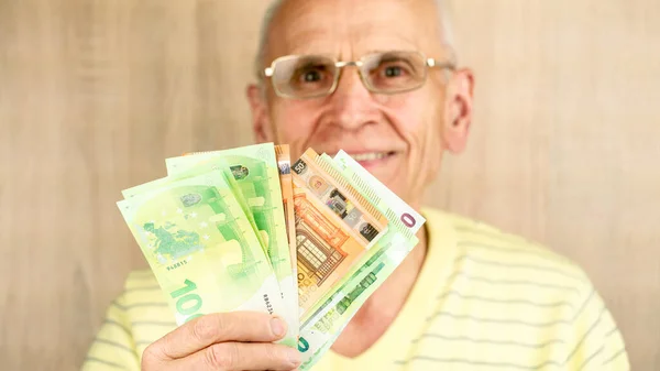 Gözlüklü emekli elinde dolar ve euro banknotlarıyla gülümsüyor