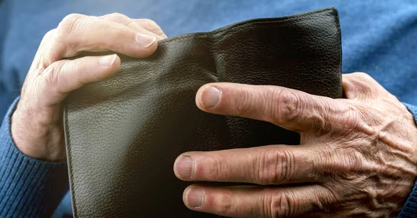 pensioner in blue sweater hands hold old black wallet