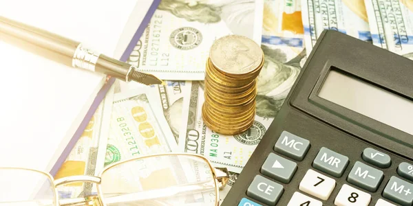 calculator banknotes coin stack and fountain pen on table