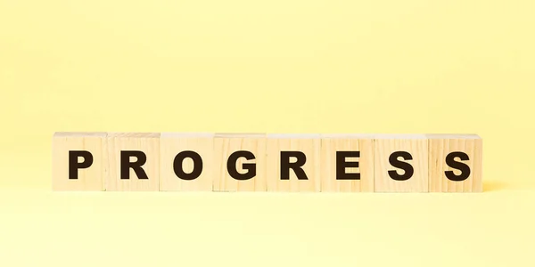 Woord vooruitgang geboekt met kleine houten blokken op geel — Stockfoto