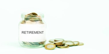 Cam kavanozun yanına saçılmış sikkeler ve emeklilik işaretleri.