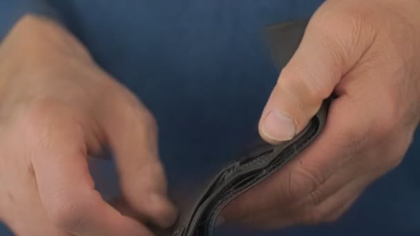 Пенсійні руки відкривають чорний порожній гаманець, шукаючи гроші — стокове відео