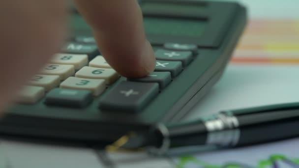 Osoba wciska klawisze kalkulatora na zamazanym piórze fontanny — Wideo stockowe