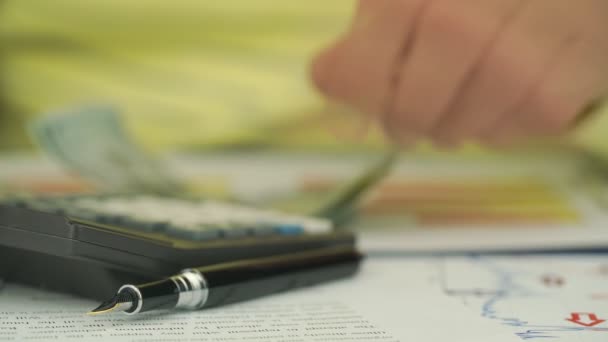 Blurry pensioner counts currency with black calculator — Stock Video