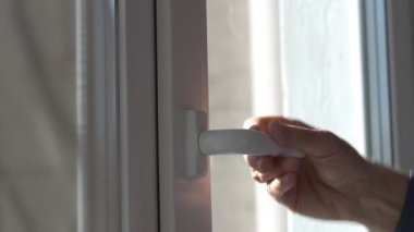 Yaşlı insan eli beyaz plastik sapıyla pencereyi açar