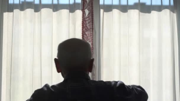 Hombre mayor silueta abre cortinas de ventana para ver la luz del sol — Vídeo de stock