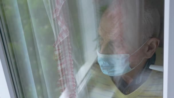 Maskeli yaşlı adam pencere genel görünümünde depresif — Stok video