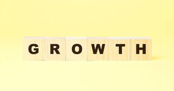 word growth with black letters on wooden blocks on yellow