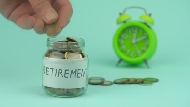 Penzista hází mince do sklenice na důchod podle budíku — Stock video