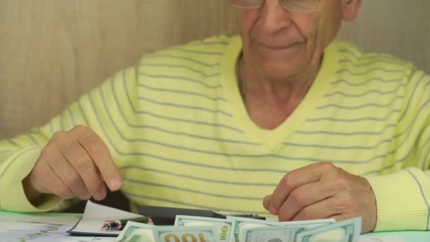 안경을 쓴 노인 이 달러 지폐를 모아 주머니에 넣는다 — 비디오