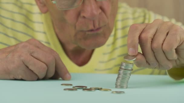 Pensionista concentrado en jersey amarillo pone monedas en la pila — Vídeo de stock