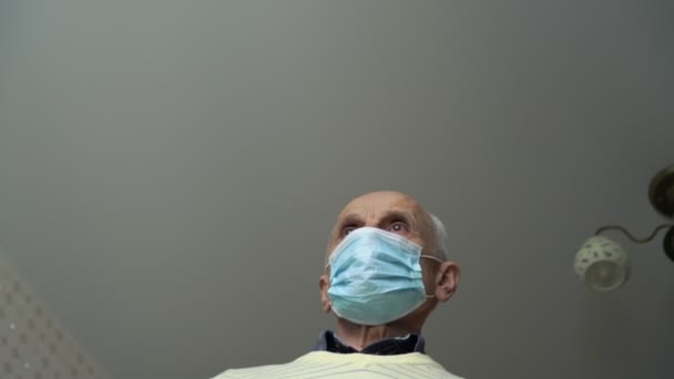 Senior man in disposable mask and yellow pullover walks — Stock Video