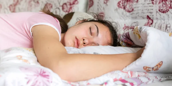 Teenage brunette in purple t-shirt sleeps on large bed — Stock Photo, Image