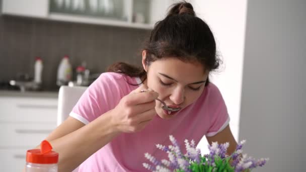 Schoolmeisje in roze t-shirt eet soep in keuken met mam — Stockvideo