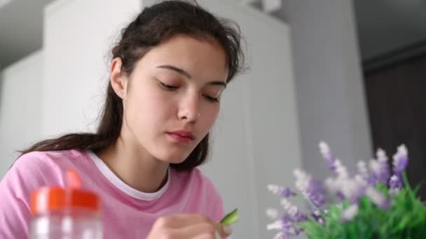 Adolescente de pelo largo come pepino y sopa sentado en la mesa — Vídeos de Stock