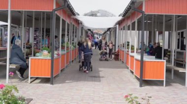 Maskeli insanlar markette tezgahlarla dolaşıyorlar.
