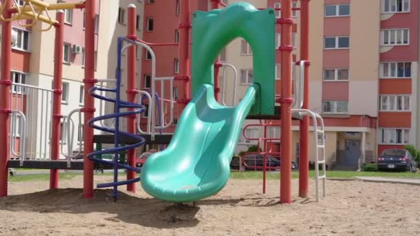 빈 건물 마당에 있는 아이들을 위한 녹색 플라스틱 슬라이드 — 비디오
