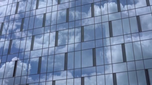 Ventanas del edificio de rascacielos reflejan cielo azul y nubes blancas — Vídeo de stock