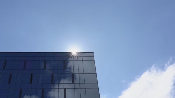 Сонячний диск з'являється за стіною хмарочоса з вікнами — стокове відео