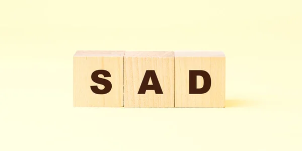 Λέξη λυπημένος με μαύρα γράμματα σε ξύλινους κύβους κατά κίτρινο — Φωτογραφία Αρχείου