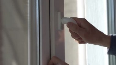 Yaşlı adam eli plastik pencere kolunu açar, hava odasını kapatır.