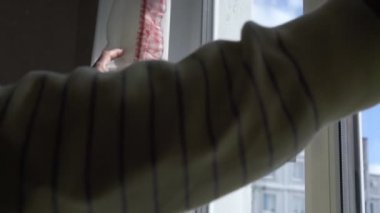 Erkek elleri plastik pencerenin beyaz perdelerini kapatır.
