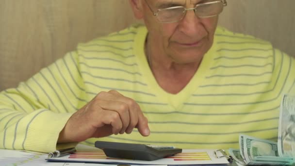 안경을 쓴 노인, 달러화 지폐 계산 — 비디오