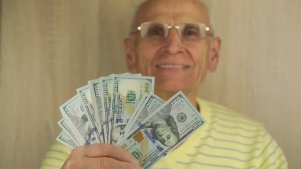 Усміхнений чоловік в окулярах показує сотні доларів у вентиляторі — стокове відео