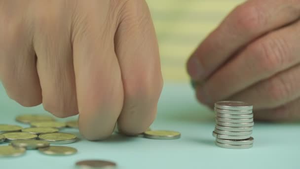 Anciano recoge monedas de oro y pone en la pila en la mesa — Vídeo de stock