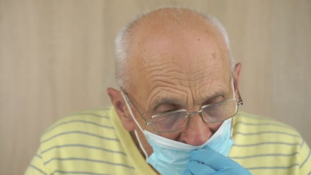 Stárnoucí muž v brýlích a sterilních rukavicích fixuje jednorázovou masku — Stock video